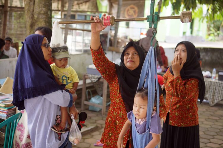 petugas menimbang berat badan balita