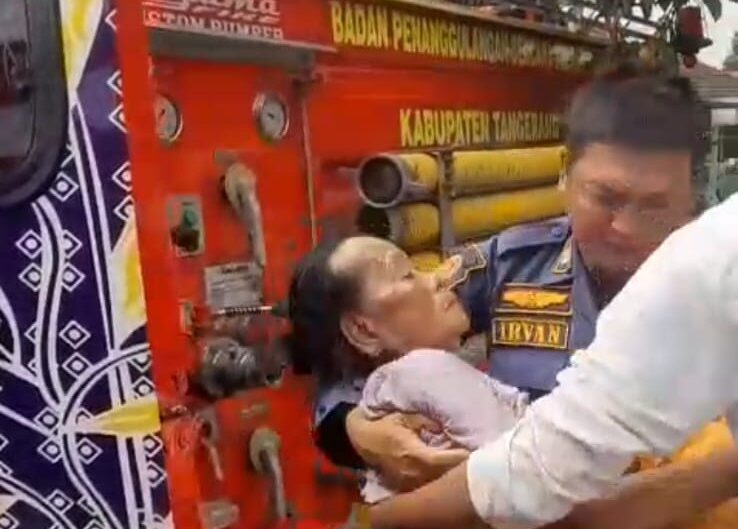 petugas damkar kabupaten tangerang tengah mengevakusi seorang nenek menggunakan mobil pemadam kebakaran